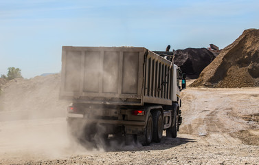 dump truck on a dusty road delivers crushed stone