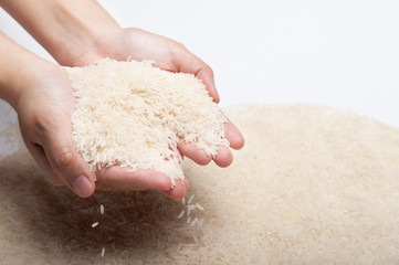 Two woman's hands holding jasmine rice, rice falling from hands