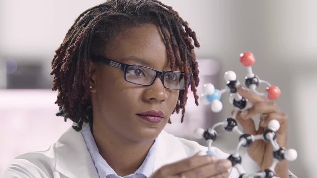 Black female scientist holding a model of a molecule