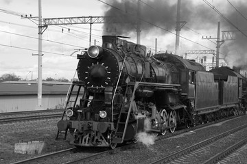 Naklejka premium Czarno-biały pociąg parowy retro w chmurach dymu jeździ koleją, tocząc się turyści