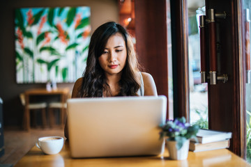 Beautiful woman working with laptop computer at coffee shop cafe