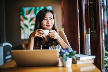 Beautiful woman working with laptop computer at coffee shop cafe