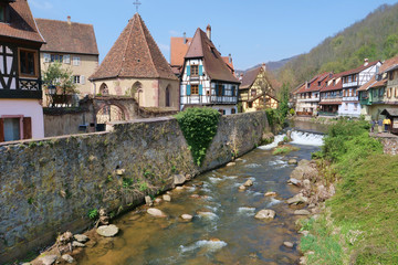 Fototapeta na wymiar Medieval half-timbered houses behind an ancient wall next to a quiet stream