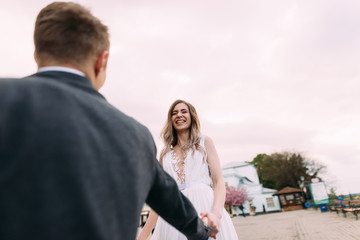 the groom holds the bride by the hands and circles her.