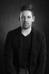 young stylish man in a blazer against a dark background