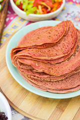 Red homemade asian pancakes with turmeric powder. Hot and fresh. On plate. Above view.