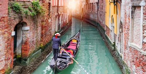 Fototapeten Venezianischer Gondoliere stochert Gondel durch das grüne Kanalwasser von Venedig Italien © muratart