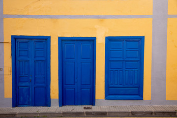 Blue wooden doors and window in yellow wall