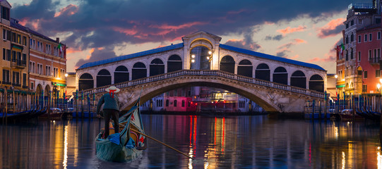 Venezianischer Gondoliere stochert Gondel durch das grüne Kanalwasser von Venedig Italien