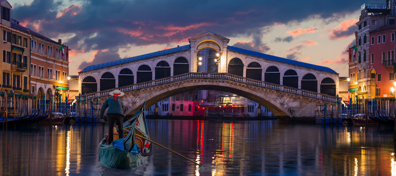 Venetian gondolier punting gondola through green canal waters of Venice Italy