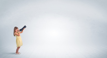 Cute little girl looking through spyglass to an empty space
