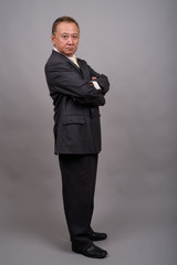 Obraz na płótnie Canvas Portrait of mature Asian businessman against gray background