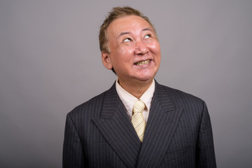 Portrait of mature Asian businessman against gray background