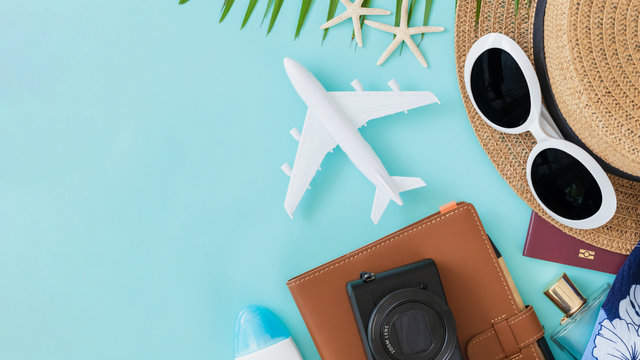 Top view of traveler accessories, tropical palm leaf and airplane on blue background with empty space for text. Travel summer holiday vacation banner concept.