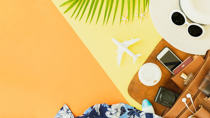 Top view of traveler accessories, tropical palm leaf and airplane on yellow and orange background with copy space for text.Travel summer holiday vacation concept.