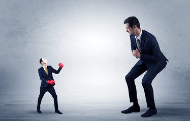 Fototapeta premium Big businessman being afraid of small masked businessman with box gloves in an empty room concept 