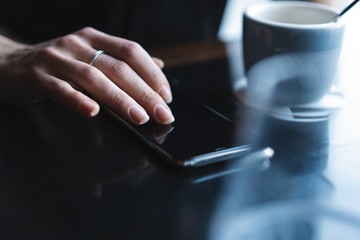 Close up of women's hands holding smartphone, female using mobile phone during coffee break.