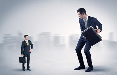 Fototapeta premium Giant businessman being afraid of small serious executor with suitcase 