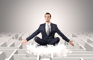 Young businessman meditate in yoga position on a cloud with infinity maze concept
