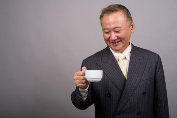 Portrait of mature Asian businessman against gray background