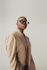 fashionable african american girl posing in sunglasses and beige jacket isolated on grey - obrazy, fototapety, plakaty