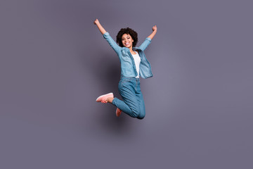 Full length side profile body size photo beautiful she her dark skin lady jump high arms hands raised up air champion triumphant glory luck wear casual jeans denim shirt isolated grey background