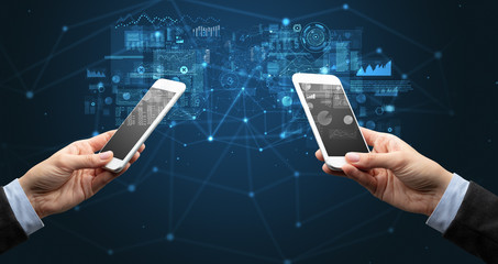 Close up of two hands holding smartphones to sync business data