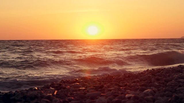 Big waves on a sea beach at sunset. Beautiful waves of slow motion video on the background of the orange sun