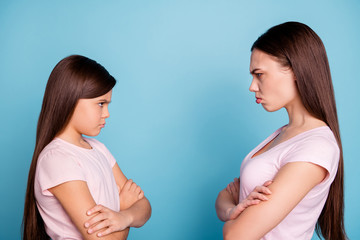 Close-up profile side view portrait of two attractive evil fury irritated annoyed displeased straight-haired girls disagree folded arms isolated over bright vivid shine green blue turquoise background