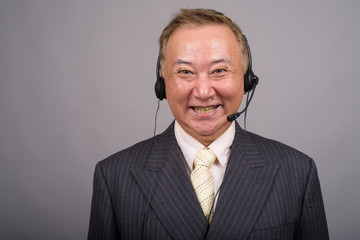 Portrait of mature Asian businessman against gray background
