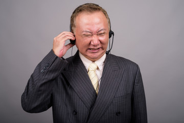 Portrait of mature Asian businessman against gray background