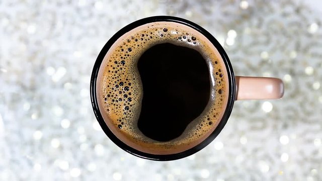 Fragrant black coffee in a cup. Smoke from black hot coffee. Advertising coffee. Glitter lights background. defocused.