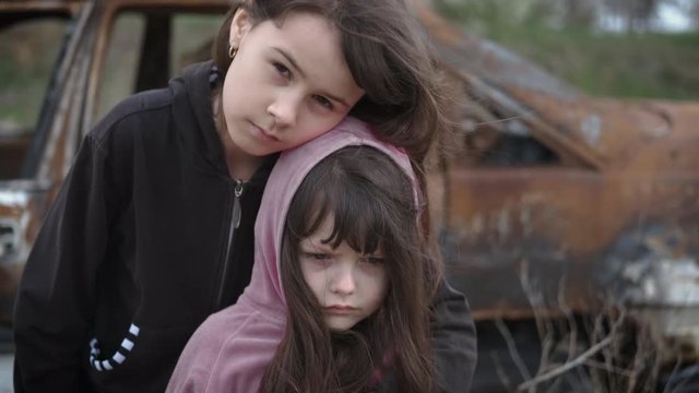 Depressed children. Child loneliness. Homeless little sisters in a junkyard. Children after the war. Little orphans.