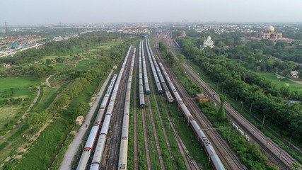 Fototapeta na wymiar Aerial bird view of railway yard of India, transportation hub showing the different trains parked next to each, further below showing vehicles moving over railway yard.
