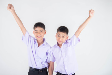 Little Asian sibling boys in student uniform pose together on white background