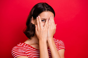 Close up photo of pretty nice charming teen teenager carefree careless close hands face feel satisfied positive cheerful satisfied content enjoy dressed striped t-shirt isolated over red background