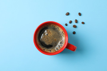 Cup of coffee with frothy foam and coffee beans on color background, space for text and top view. Coffee time accessories
