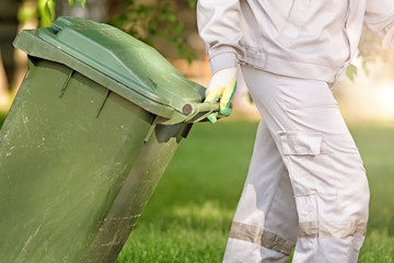 cleaning person moving by hand trash can for garbage recycling closeup side view of green plastic waste bin at city park outdoor clean nature action pollution concept authentic lifestyle photo