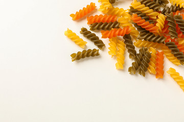 Color pasta on white background, space for text. Dry uncooked whole pasta