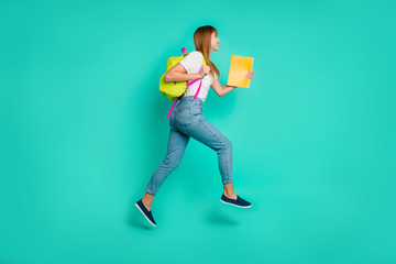Full length side profile body size photo beautiful she her lady jump high arms hands hold back pack notebooks on way school friendly wear specs casual white t-shirt isolated teal green background