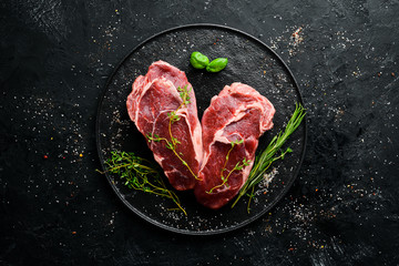 Raw Steak Ribeye. On a black stone table. Top view. Free space for your text.