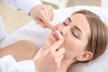 Fototapeta na wymiar Beautician removing hair above upper lip of young woman in salon