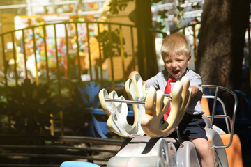little boy with a red tie riding a carousel