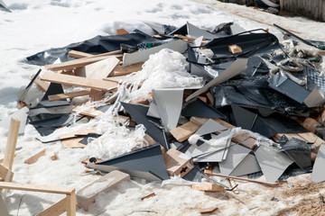 debris with roof scraps stored near house under construction in winter