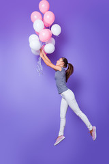Fototapeta na wymiar Vertical full length body size profile side view of her she nice-looking attractive cheerful cheery girl having fun flying with helium balls isolated over violet purple vivid shine bright background