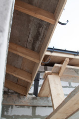 close up view of scaffolding and house under construction with holders for gutters water drainage system of roof