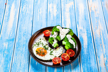 Fried egg with vegetables on wooden table