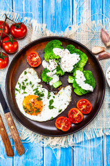 Fried egg with vegetables on wooden table