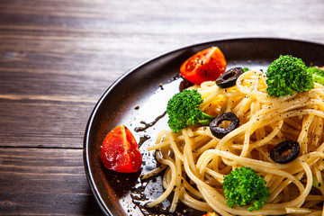 Pasta with herbs and vegetables on wooden background
