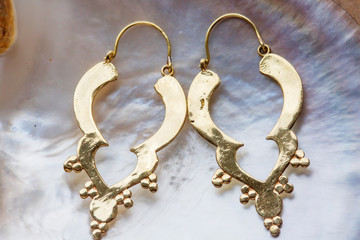 Boho style brass big decorative earrings on pearl background